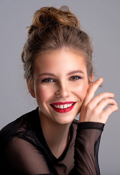young-girl-posing-in-the-studio-on-a-grey-background-happy-caucasian-girl-smiling-at-camera-.jpg
